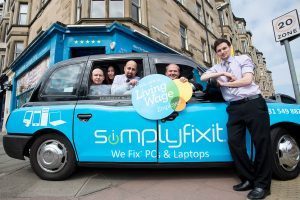 Taxi parked outside SimplyFixIt store at Bruntsfield. Several members of the SimplyFixIt team are also there, inside and outside the taxi.